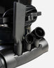 Close-up of a black cordless vacuum cleaner showing its attachments, including a crevice nozzle, a brush head, and a flexible brush attachment, with the power cord coiled behind it.