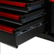 Close-up of a black and red tool chest with open drawers on a white background