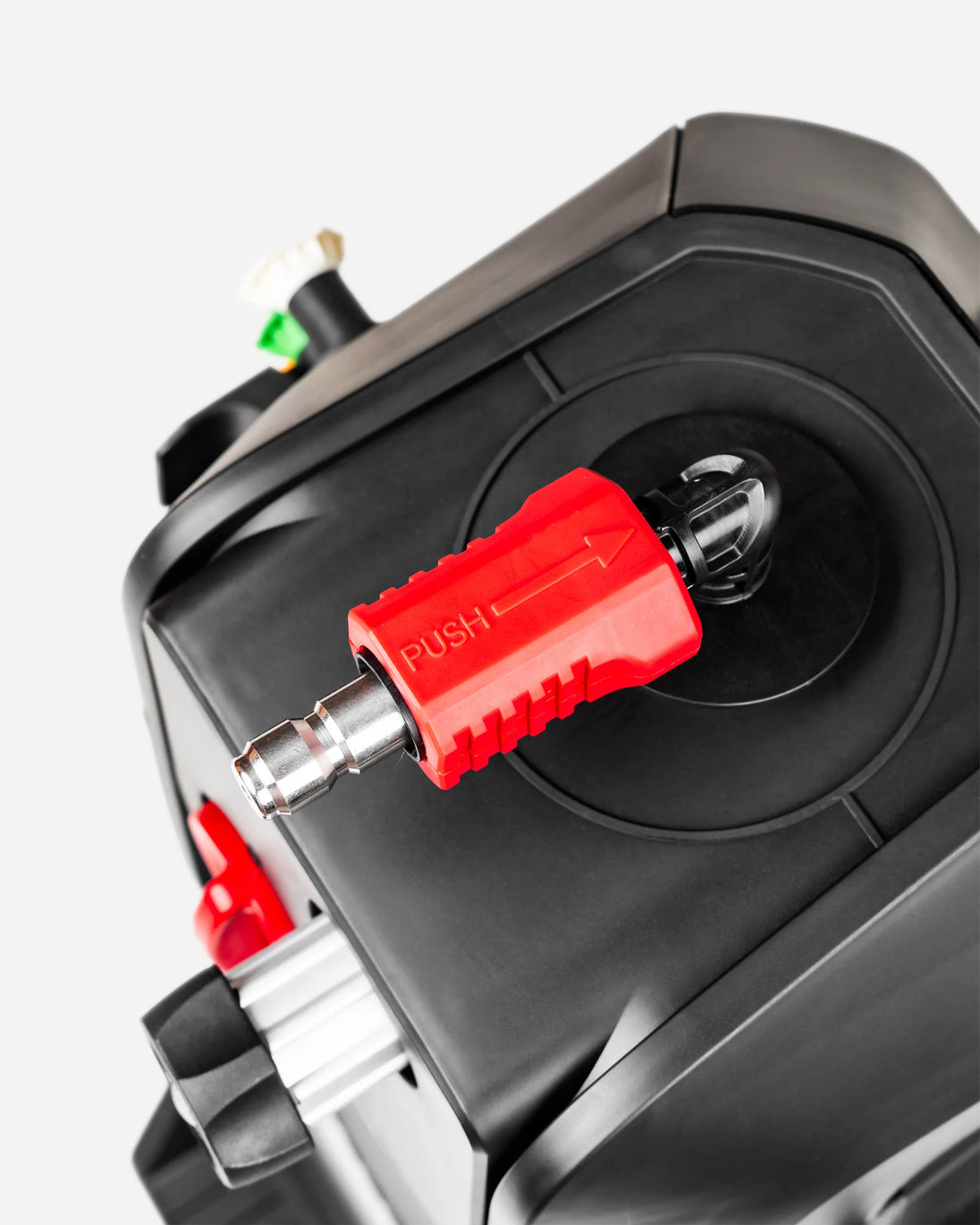 Close-up of a red plastic push-button connector with a silver metal tip mounted on a black device, shown against a light gray background.