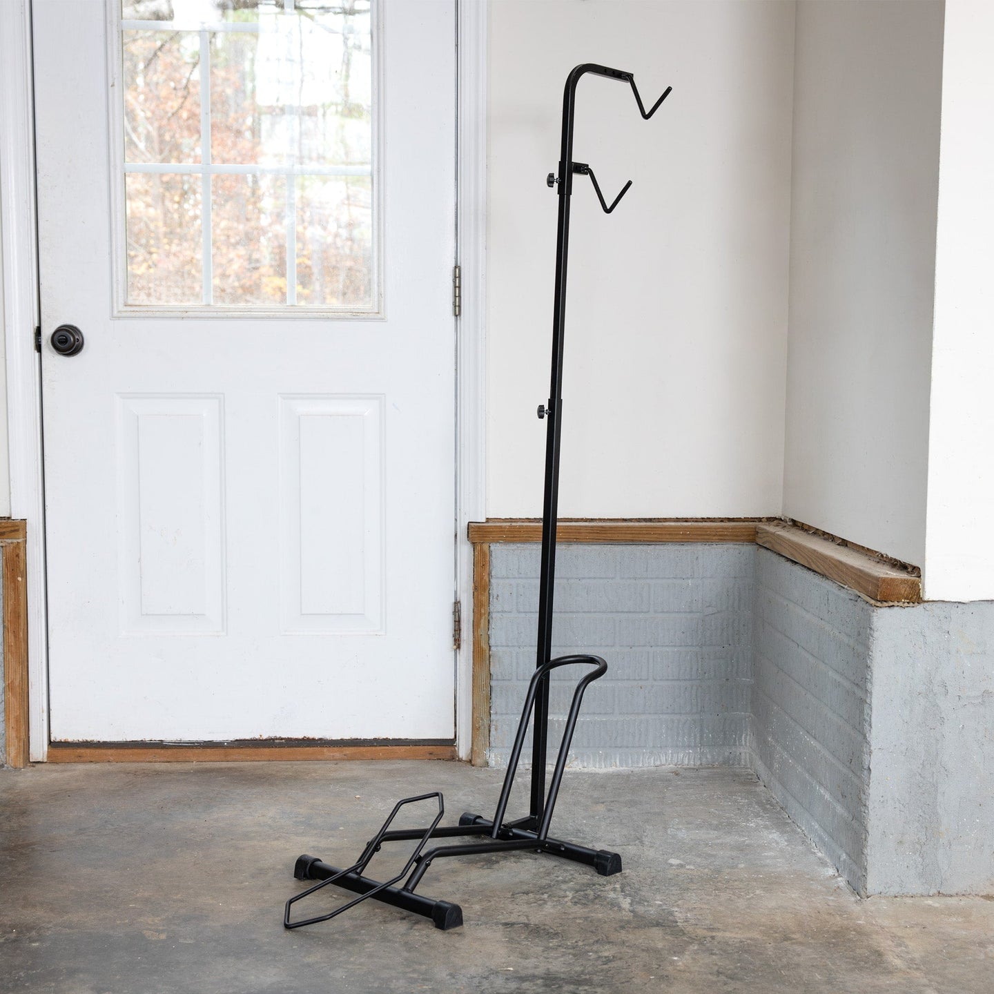 Black metal bike stand in a room with a white door and concrete floor.