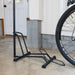 Black bike stand holding a bicycle wheel indoors.