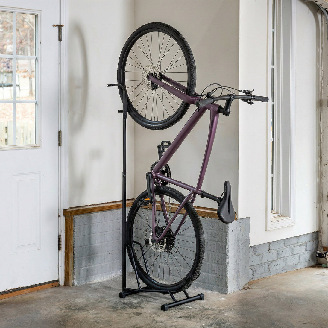 Bicycle leaning against a stand in a room with white walls and a door.