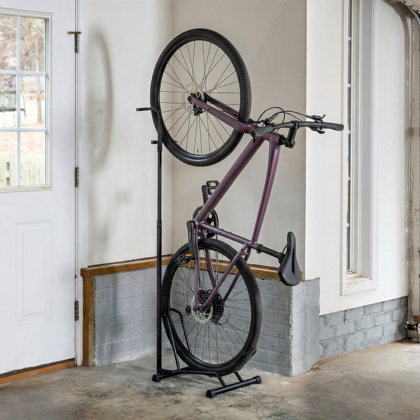 Bicycle leaning against a stand in a room with white walls and a door.