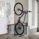 Bicycle leaning against a stand in a room with white walls and a door.